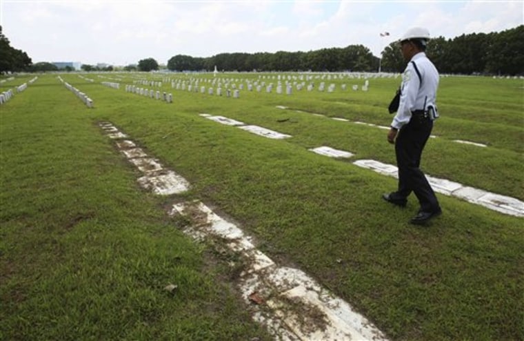 A private guard walks along soil-covered grave markers at Clark Veterans Cemetery at the sprawling Clark Economic Zone, a former U.S. Air Force base in Dau, Pampanga province in northern Philippines, in this July 1, 2011 photo.